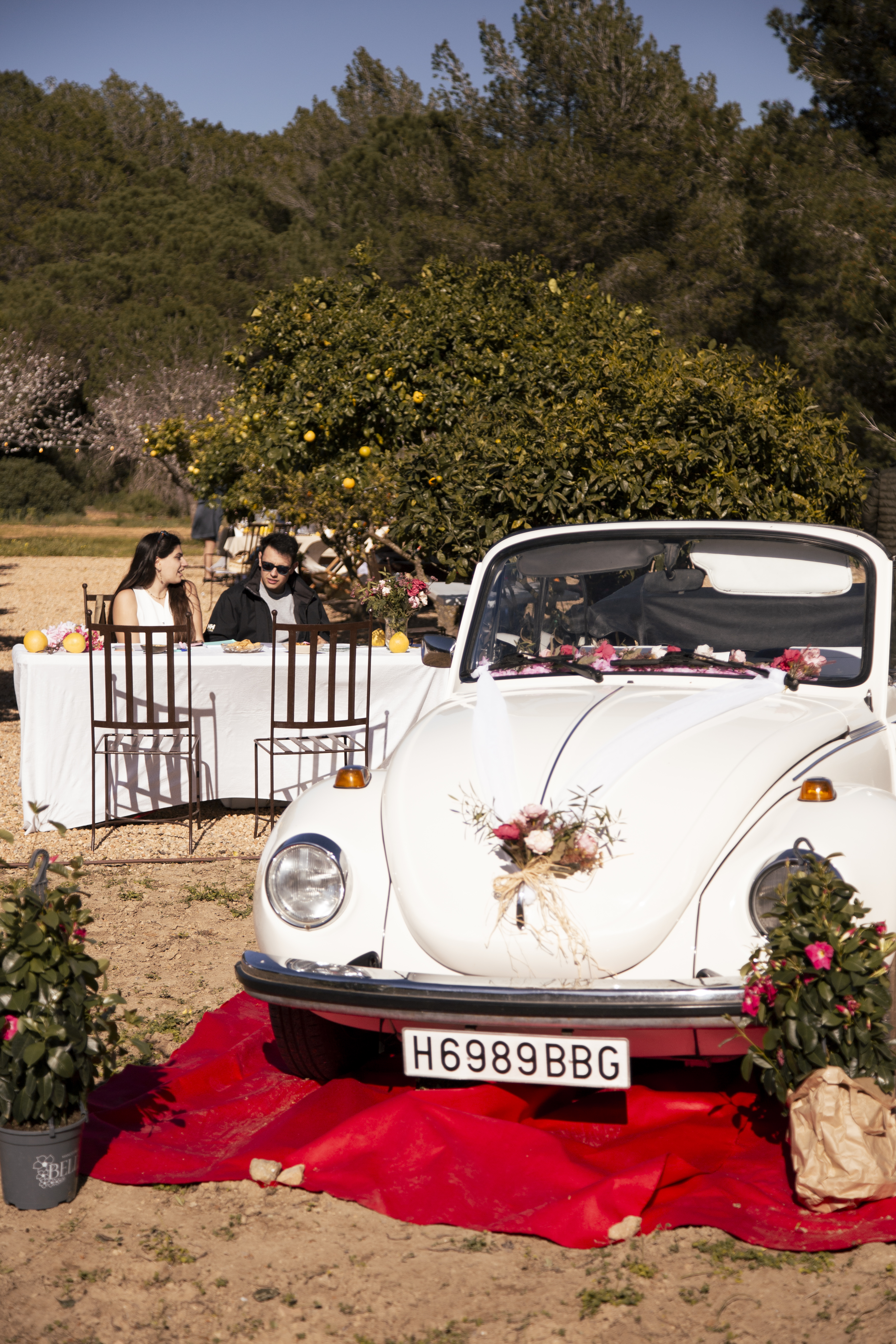 Escarabajo blanco antiguo decorado con flores en una feria de bodas en Ibiza con mesa preparada al lado